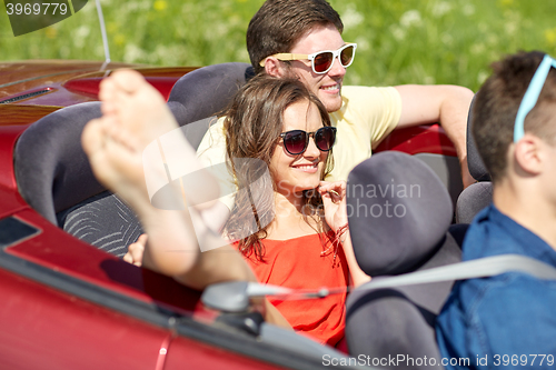 Image of happy friends driving in cabriolet car outdoors