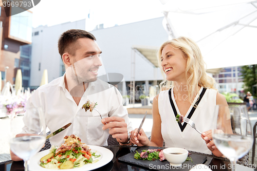 Image of happy couple eating dinner at restaurant terrace