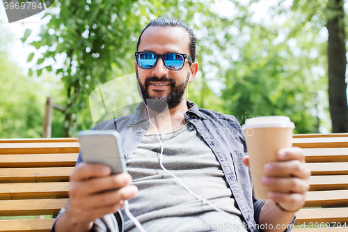 Image of man with earphones and smartphone drinking coffee