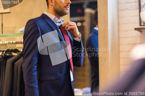 Image of close up of man trying tie on at clothing store