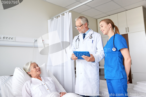 Image of doctor and nurse visiting senior woman at hospital