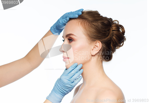 Image of surgeon or beautician hands touching woman face