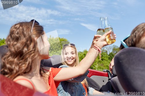 Image of happy friends driving in cabriolet car with beer