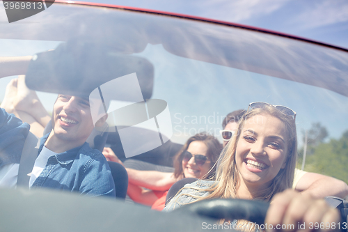 Image of happy friends driving in cabriolet car