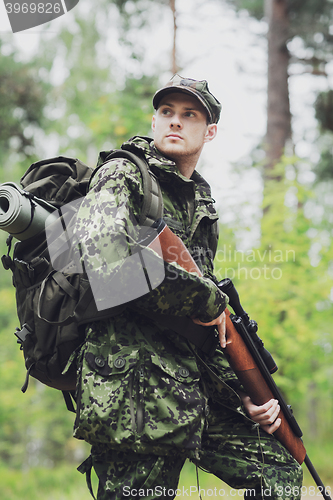 Image of young soldier or hunter with gun in forest