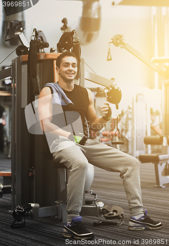 Image of smiling man exercising on gym machine