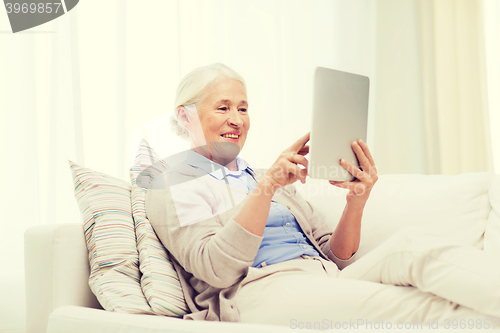 Image of happy senior woman with tablet pc at home