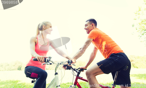 Image of happy couple riding bicycle outdoors