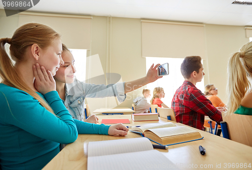 Image of student girls taking smartphone selfie at school