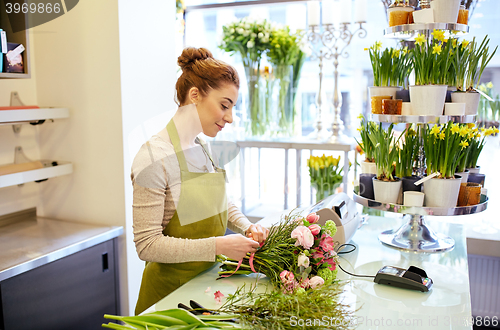 Image of smiling florist woman making bunch at flower shop