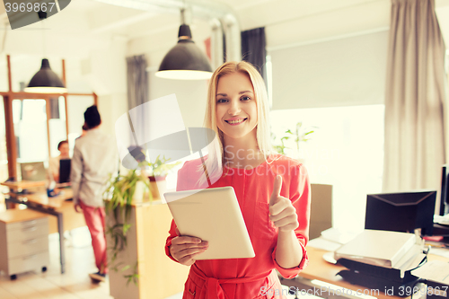 Image of woman with tablet pc showing thumbs up at office