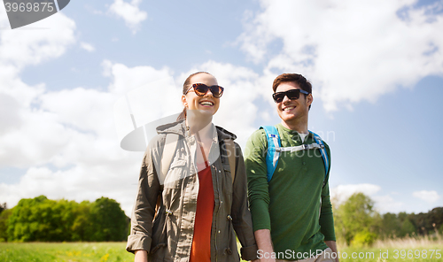 Image of happy couple with backpacks hiking outdoors