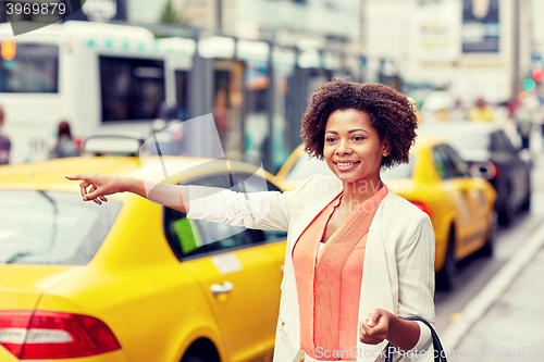 Image of happy african woman catching taxi