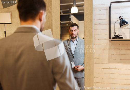 Image of man trying suit on at mirror in clothing store