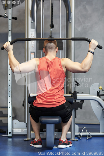 Image of man flexing muscles on cable machine gym