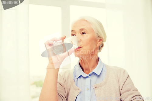 Image of happy senior woman with glass of water at home