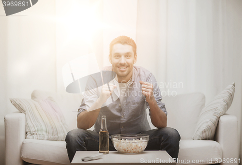 Image of smiling man watching sports at home