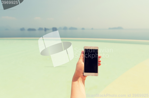 Image of close up of female hand with smartphone on beach