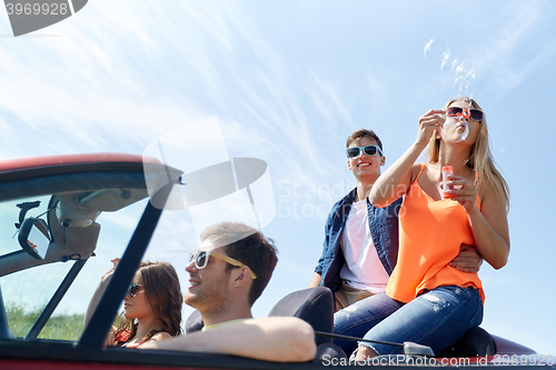 Image of friends driving in car and blowing bubbles