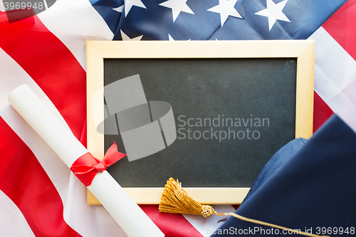 Image of board, bachelor hat and diploma on american flag