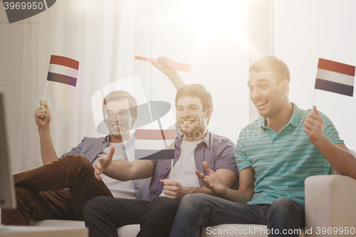 Image of happy male friends with flags and vuvuzela