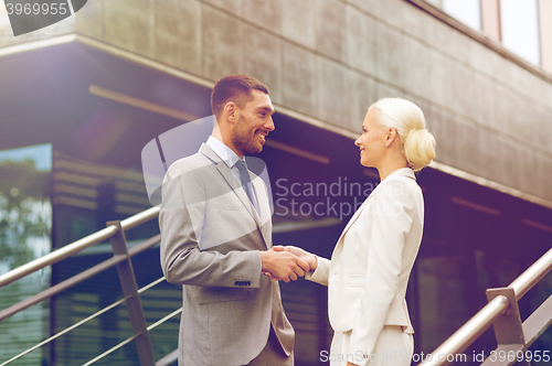 Image of smiling businessmen shaking hands on street