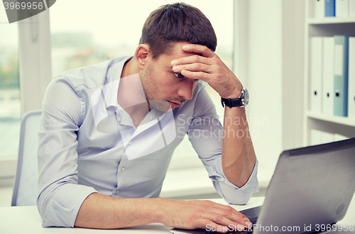 Image of stressed businessman with laptop at office