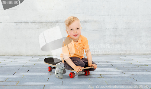 Image of happy little boy sitting on skateboard