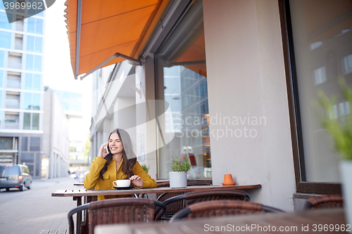 Image of happy woman calling on smartphone at city cafe