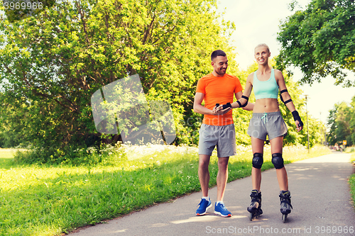 Image of happy couple with roller skates riding outdoors