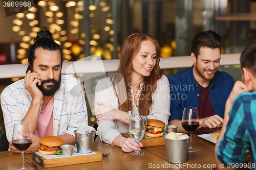 Image of man with smartphone and friends at restaurant