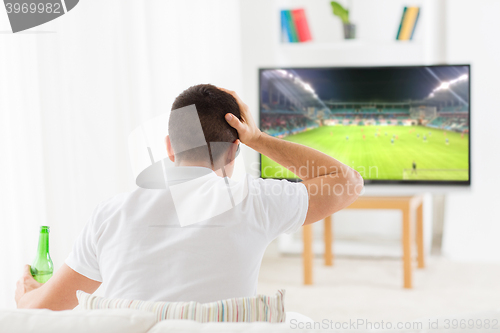 Image of man watching football or soccer game on tv at home