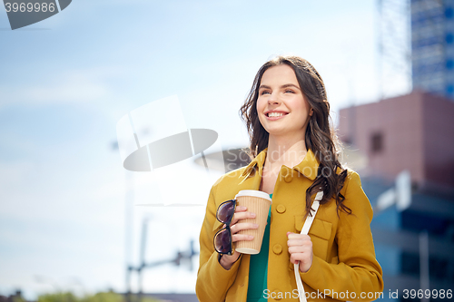 Image of happy young woman drinking coffee on city street