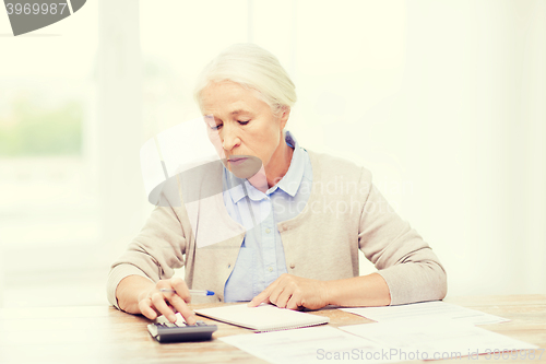 Image of senior woman with papers and calculator at home