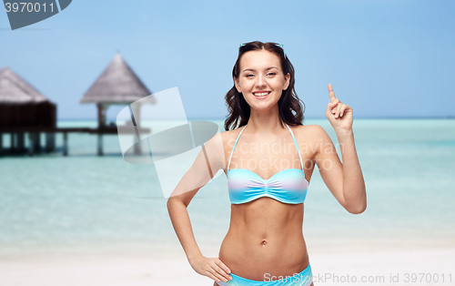 Image of happy woman in bikini swimsuit pointing finger up