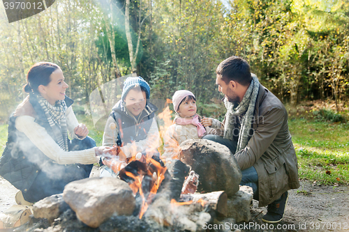 Image of happy family roasting marshmallow over campfire