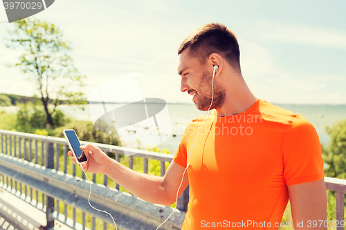 Image of smiling young man with smartphone and earphones