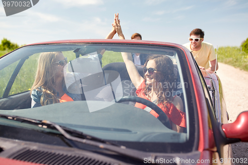 Image of happy friends pushing broken cabriolet car