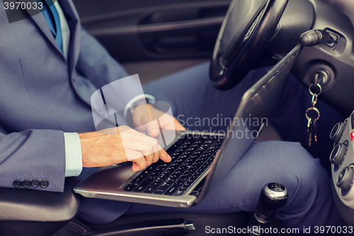 Image of close up of young man with laptop driving car