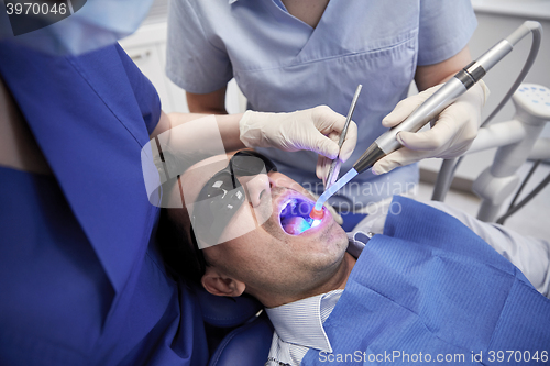 Image of dentists treating male patient teeth at clinic