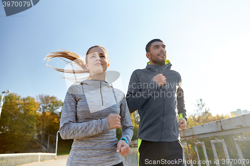 Image of happy couple running outdoors
