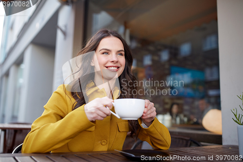 Image of happy woman drinking cocoa at city street cafe