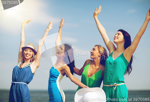 Image of girls looking at the sea with hands up