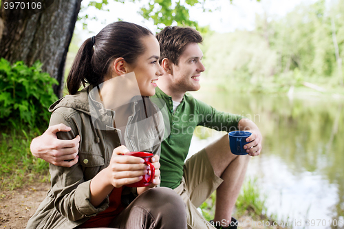 Image of happy couple with cups drinking in nature