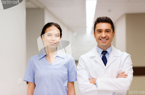 Image of smiling doctor in white coat and nurse at hospital