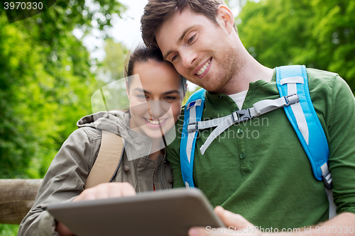 Image of happy couple with backpacks and tablet pc outdoors