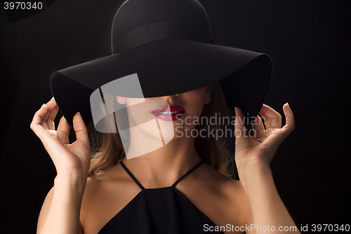 Image of beautiful woman in black hat over dark background