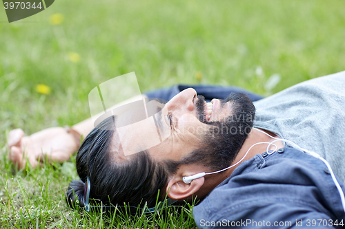 Image of man with earphones listening to music on grass