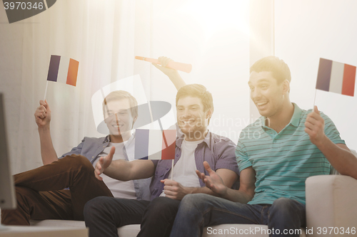 Image of happy male friends with flags and vuvuzela