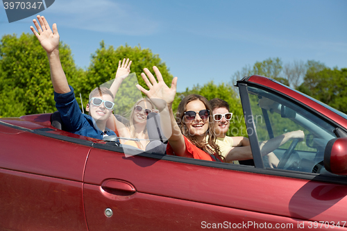 Image of happy friends driving in cabriolet car at country